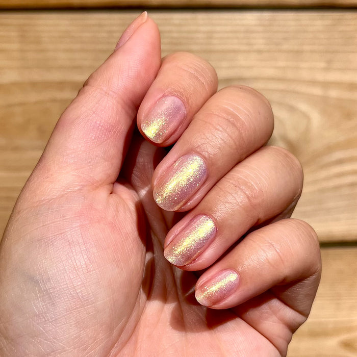 Hand showing Sugarcoat sheer pink iridescent quick dry polish on natural nails in bright natural light