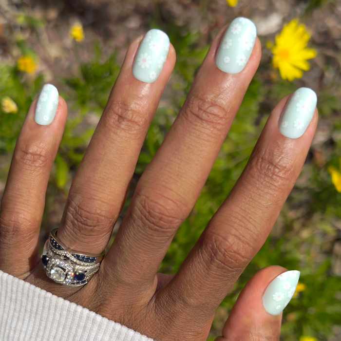 Teal Chrome Flower Shower - Press-On | Short | Round pastel teal press-on nails with white daisy mani on hand outdoors