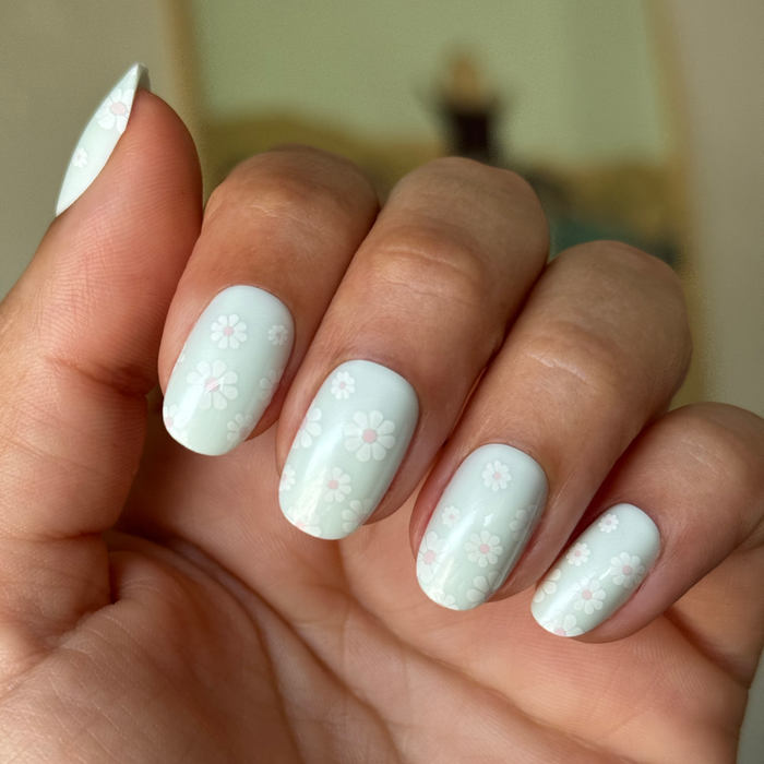 Teal Chrome Flower Shower - Press-On | Short | Round with pale teal nails and white daisy floral mani on hand indoors